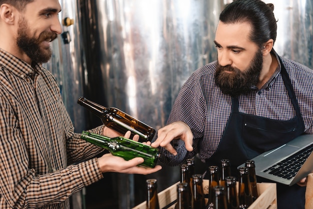 Uomo attento che sceglie le bottiglie di birra Microbrewery.