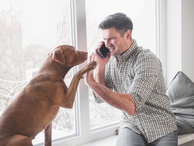 Uomo attraente che parla al telefono e adorabile cucciolo