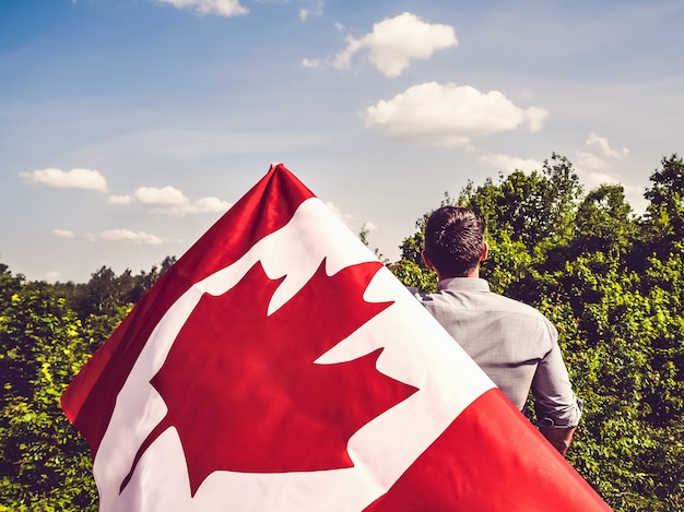 Uomo attraente che tiene bandiera canadese. festa nazionale