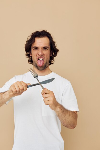 Uomo attraente in una maglietta bianca con coltello con forchetta Stile di vita inalterato