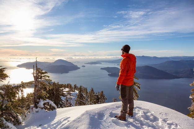 Uomo avventuroso che si gode la vista sulla cima di una montagna