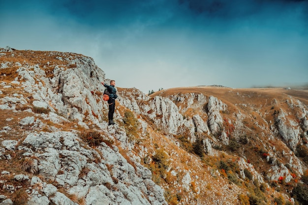 Uomo avventuroso escursionista con le mani in cima alla scogliera di roccia di montagna