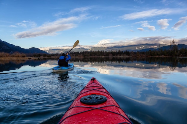 Uomo avventuroso in kayak in acque tranquille durante una giornata invernale nuvolosa