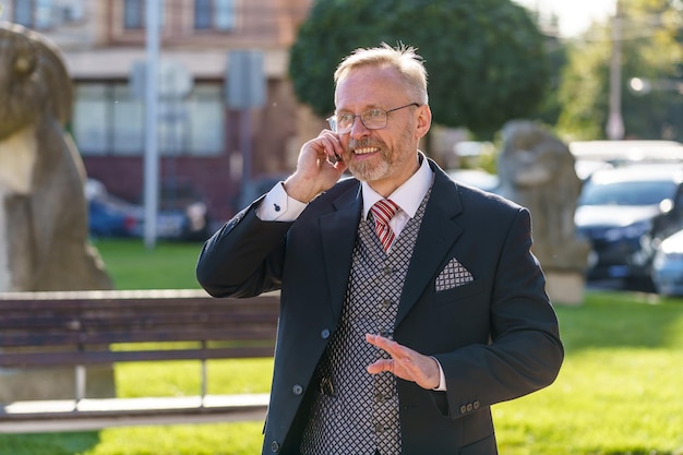 Uomo barbuto alla moda e alla moda in giacca e cravatta in chat con lo smartphone Stile aziendale Immagine alla moda Concetto di lavoratore d'ufficio