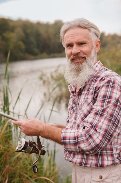 Uomo barbuto anziano che pesca su un lago