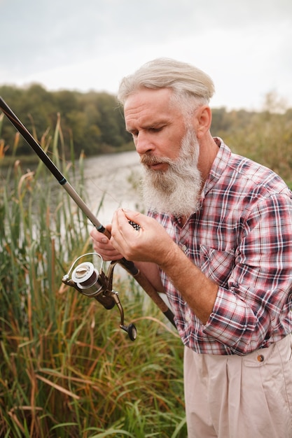 Uomo barbuto anziano che pesca su un lago