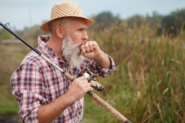 Uomo barbuto anziano che pesca su un lago