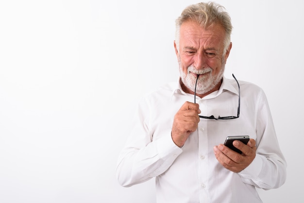 uomo barbuto anziano triste piangere mentre si utilizza il telefono cellulare e occhiali mordaci su bianco