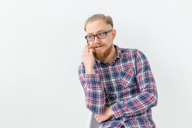 Uomo barbuto bello parlare al telefono sopra il muro bianco.