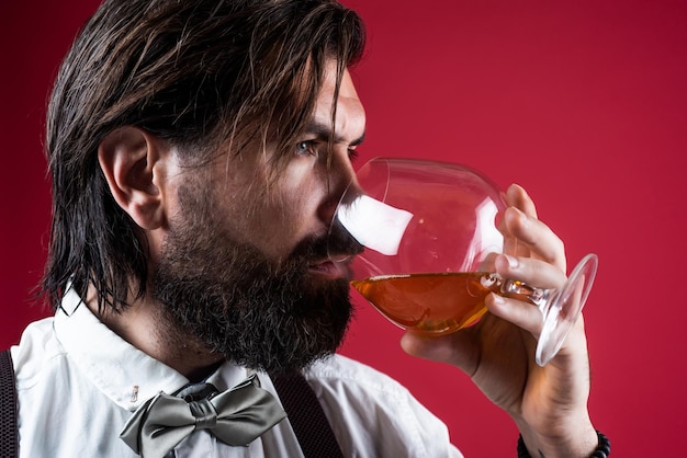 Uomo barbuto caucasico che beve cognac dalla barra di vetro