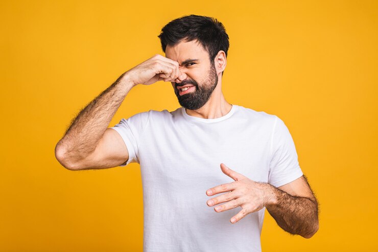 Foto uomo barbuto caucasico isolato sopra priorità bassa gialla che sente l'odore di qualcosa di puzzolente e disgustoso, intollerabile