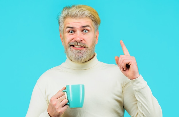 Uomo barbuto che beve caffè o tè caldo. Uomo alla moda con capelli alla moda con bevanda calda tazza.