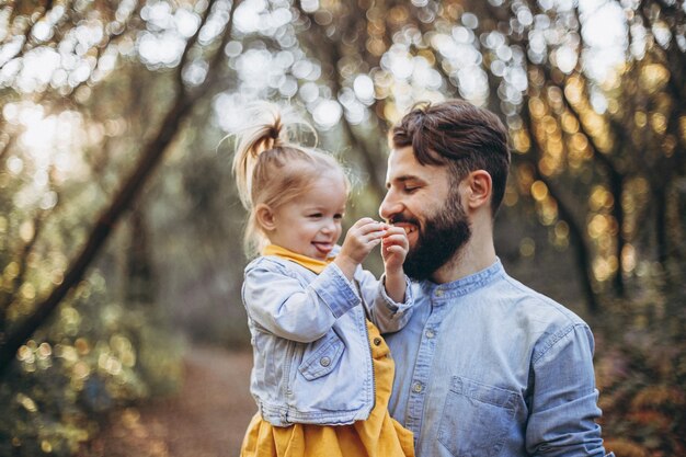 uomo barbuto che cammina nel parco autunnale insieme alla sua dolce figlia che si gode il tempo soleggiato