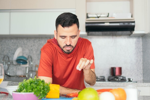 Uomo barbuto che cucina una sana insalata di frutta e verdura