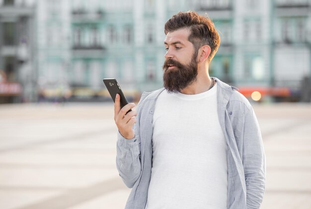 Uomo barbuto che fa una videochiamata tramite Internet mobile all'aperto Videochiamata online utilizzando un'applicazione mobile Utente Internet mobile Comunicazione mobile
