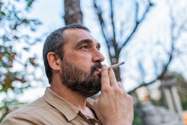 Uomo barbuto che fuma per strada