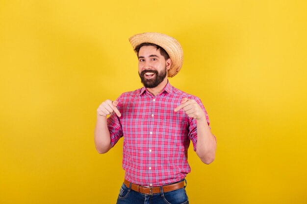 Uomo barbuto che indossa abiti tipici da festa Junina dicendo qui solo qui con le mani Per la festa di Arraia