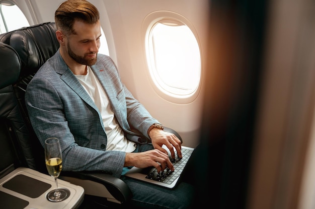 Uomo barbuto che lavora al computer portatile in aeroplano