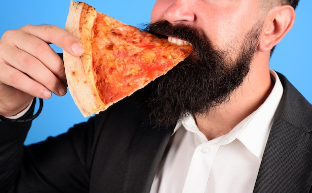 Uomo barbuto che mangia pizza uomo che mangia una fetta di pizza fresca e calda uomo barbuto che mangia una fetta di pizza