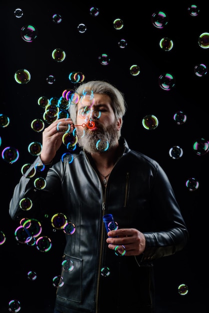 Uomo barbuto che soffia bolle di sapone gioca con gonfiare bolle felicità buon umore infanzia