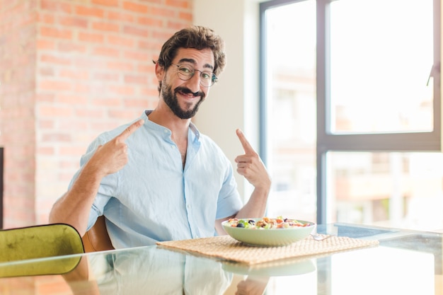 Uomo barbuto che sorride fiduciosamente indicando il proprio ampio sorriso, atteggiamento positivo, rilassato e soddisfatto