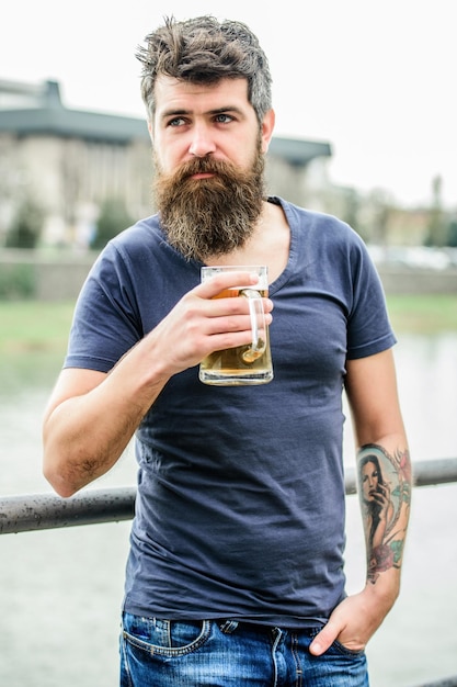 Uomo barbuto con bicchiere di birra weekend all'aperto relax maschio brutale ha bisogno di ristoro bevanda birra alcolica bevanda hipster maturo con barba capelli che bevono birra evviva al successo