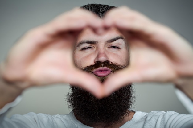 Uomo barbuto con le mani a forma di cuore