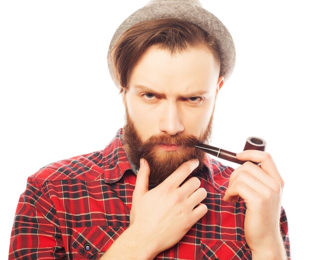 Uomo barbuto con un cappello che fuma la pipa. Isolato su bianco.