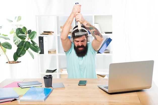 Uomo barbuto cuffie ufficio martello smartphone Comunicazione viziata Negoziazioni mobili fallite La cosa più fastidiosa del lavoro nel call center Chiamata in arrivo Lavoro stressante al call center