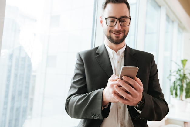 Uomo barbuto di affari che per mezzo dello smartphone