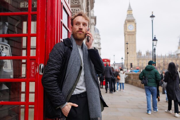 Uomo barbuto elegantemente vestito che parla sullo smartphone