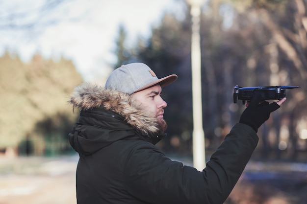 Uomo barbuto hipster con in mano un drone volante