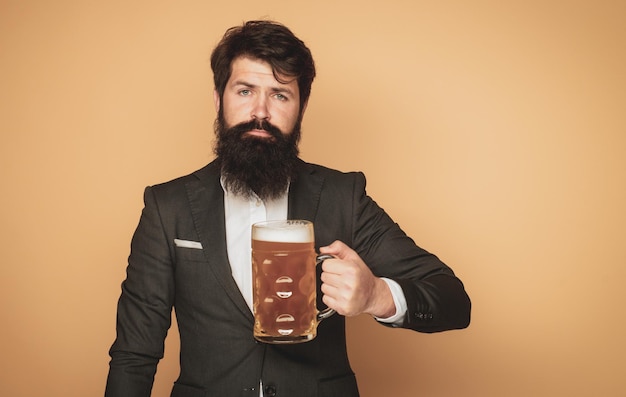 Uomo barbuto in abito nero con un bicchiere di birra uomo elegante felice che beve birra pub e bar di birra essere