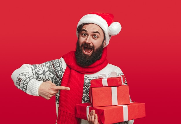 uomo barbuto in cappello della Santa che punta alla pila di scatole regalo