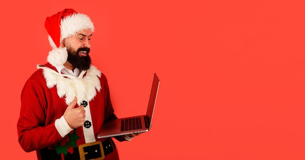 Uomo barbuto in costume di Babbo Natale con laptop mostra ok segno comunicazione tecnologia moderna