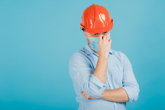 uomo barbuto in un casco protettivo arancione e maschera su sfondo blu