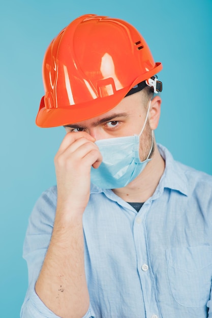 uomo barbuto in un casco protettivo arancione e maschera su sfondo blu