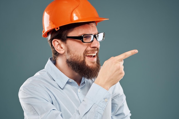 Uomo barbuto in vernice arancione e occhiali lavori di costruzione sfondo blu