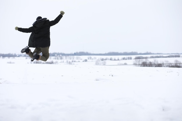 Uomo barbuto nei boschi invernali. Attraente giovane felice con la barba a piedi nel parco.