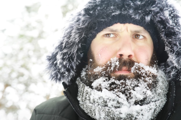 Uomo barbuto nei boschi invernali. Attraente giovane felice con la barba a piedi nel parco.