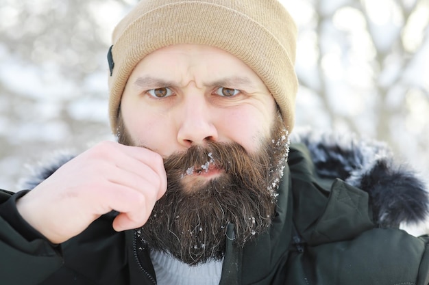 Uomo barbuto nei boschi invernali. Attraente giovane felice con la barba a piedi nel parco.