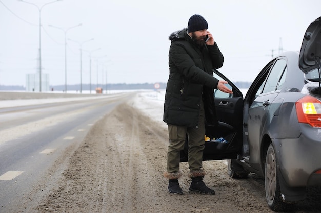 Uomo barbuto nei boschi invernali. Attraente giovane felice con la barba a piedi nel parco.