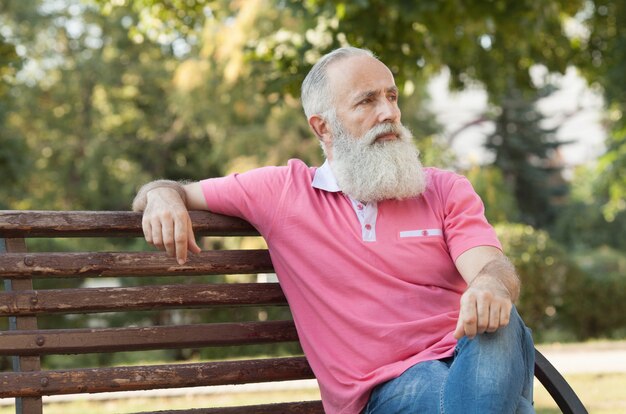 Uomo barbuto seduto su una panchina nel parco