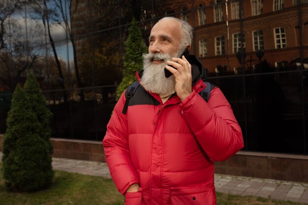 Uomo barbuto senior sorridente che fa una telefonata.