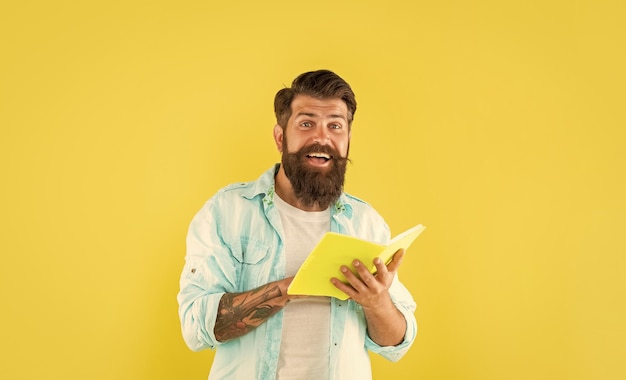 Uomo barbuto sorpreso con libro su sfondo giallo sorpresa