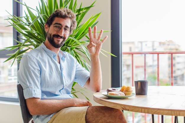 Uomo barbuto sorridente e dall'aspetto amichevole, che mostra il numero quattro o il quarto con la mano in avanti, conto alla rovescia