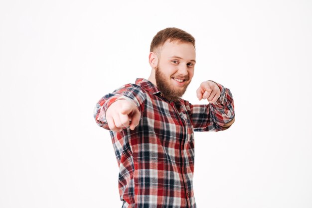 Uomo barbuto sorridente in camicia che indica nella parte anteriore