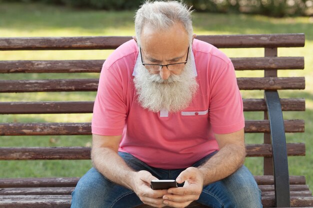 Uomo barbuto su una panchina utilizzando un telefono