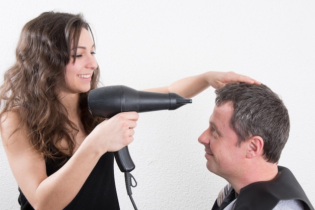 Uomo bello al parrucchiere che asciuga i capelli