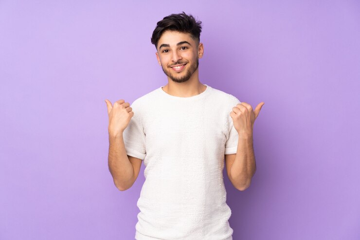 Foto uomo bello arabo sopra la parete isolata con i pollici aumenta il gesto e sorridere